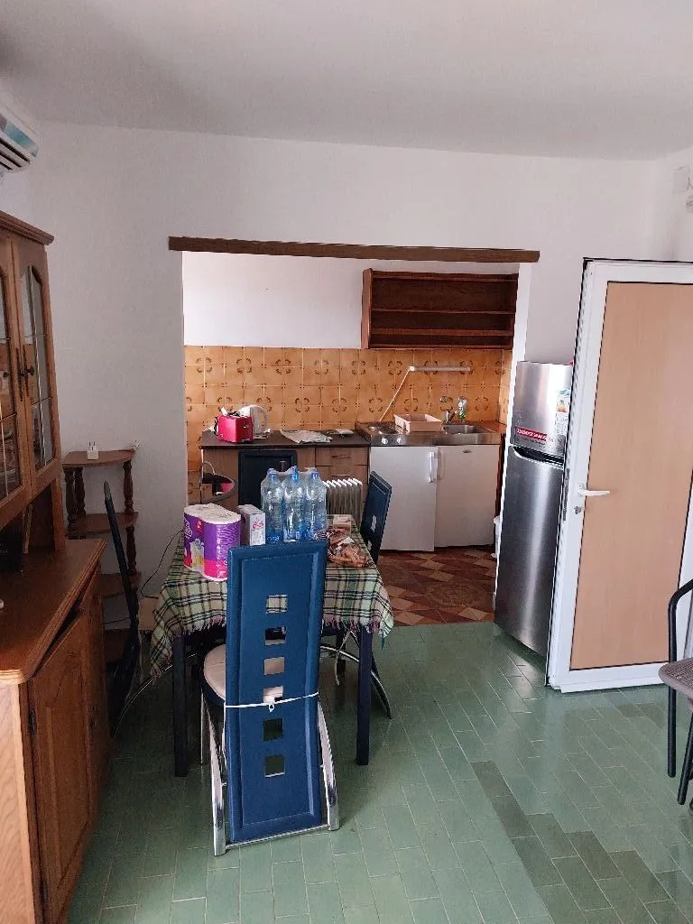 Kuhinja sa trpezarijskim stolom i frižiderom.