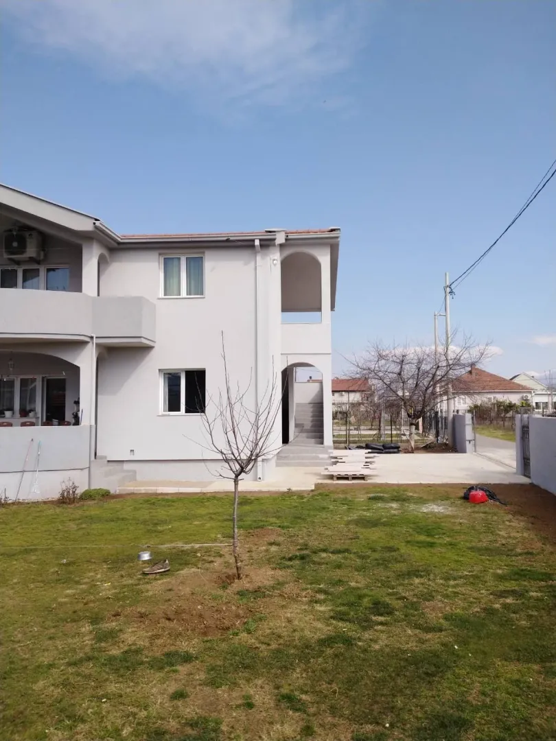 Yard in front of a modern two-story house with a grey facade.