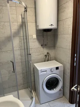 A modern bathroom with a shower cabin, washing machine, and water heater. - image 8