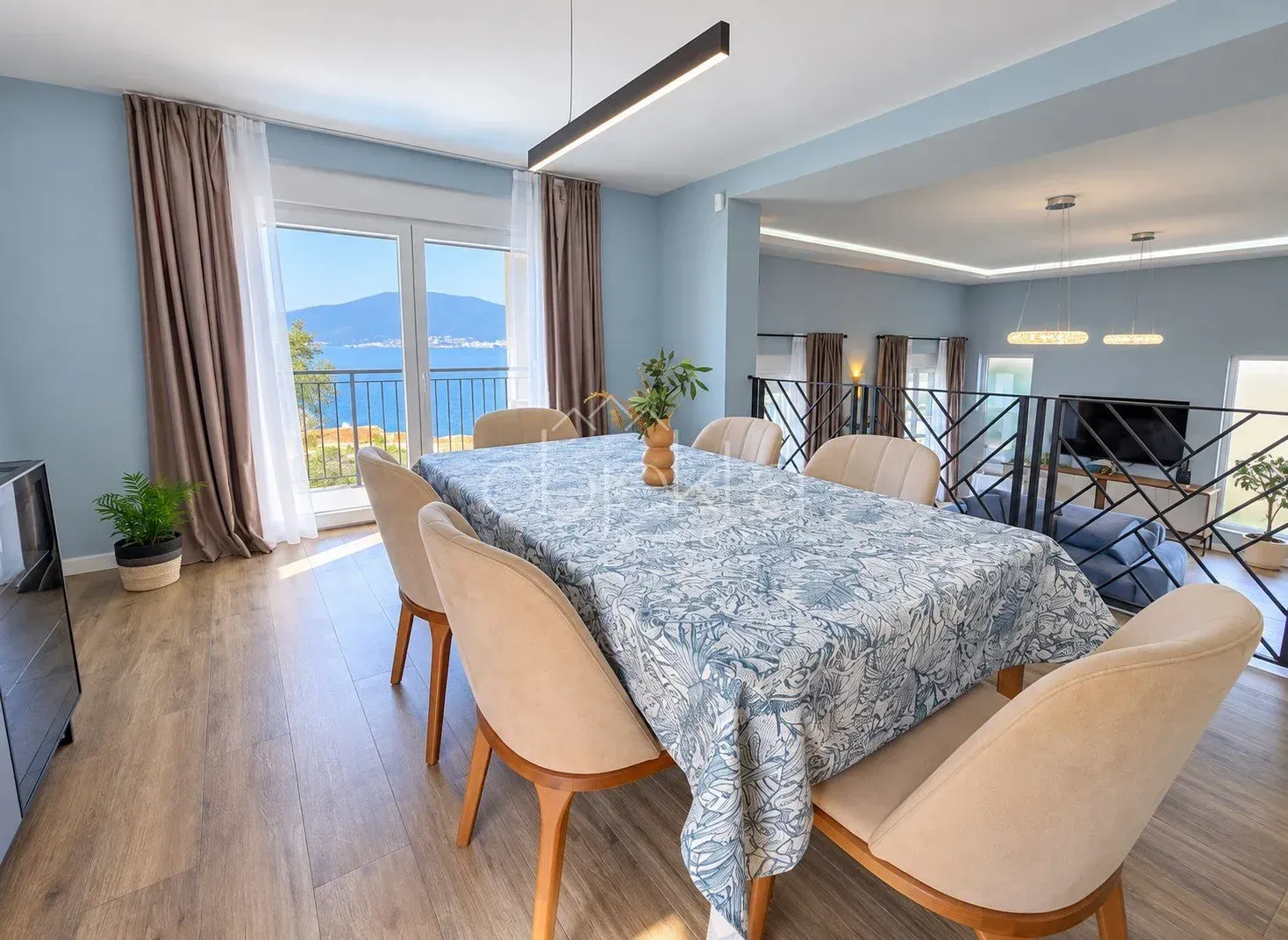 Spacious dining area with a large table, chairs, and a sea view.