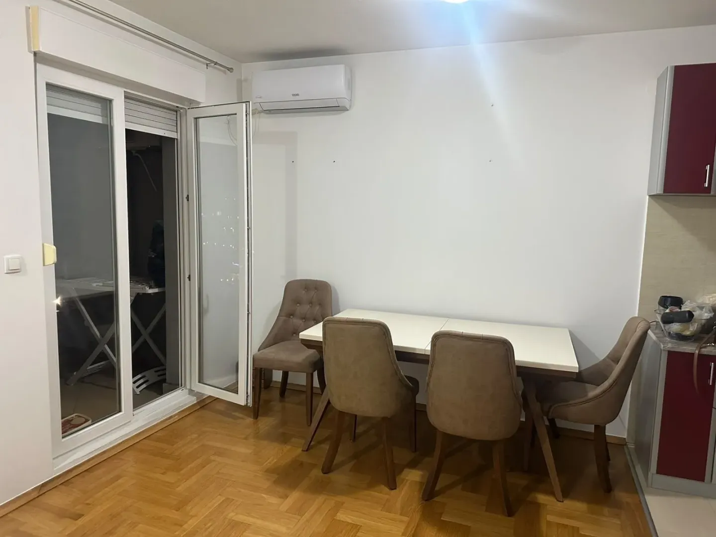 Trpezarija sa stolom, stolicama i izlazom na terasu.