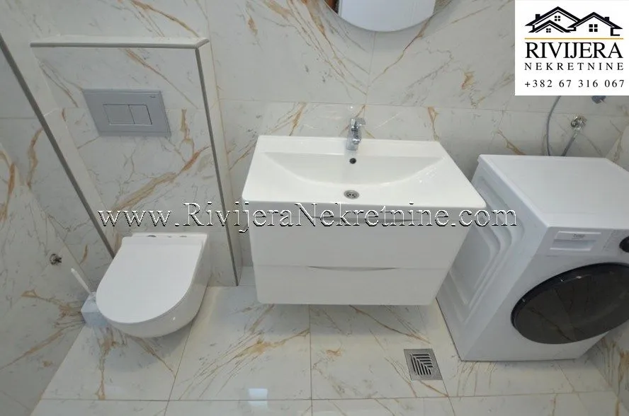 Moderne kupatilo sa umivaonikom, ugradnim WC šoljom i veš mašinom.