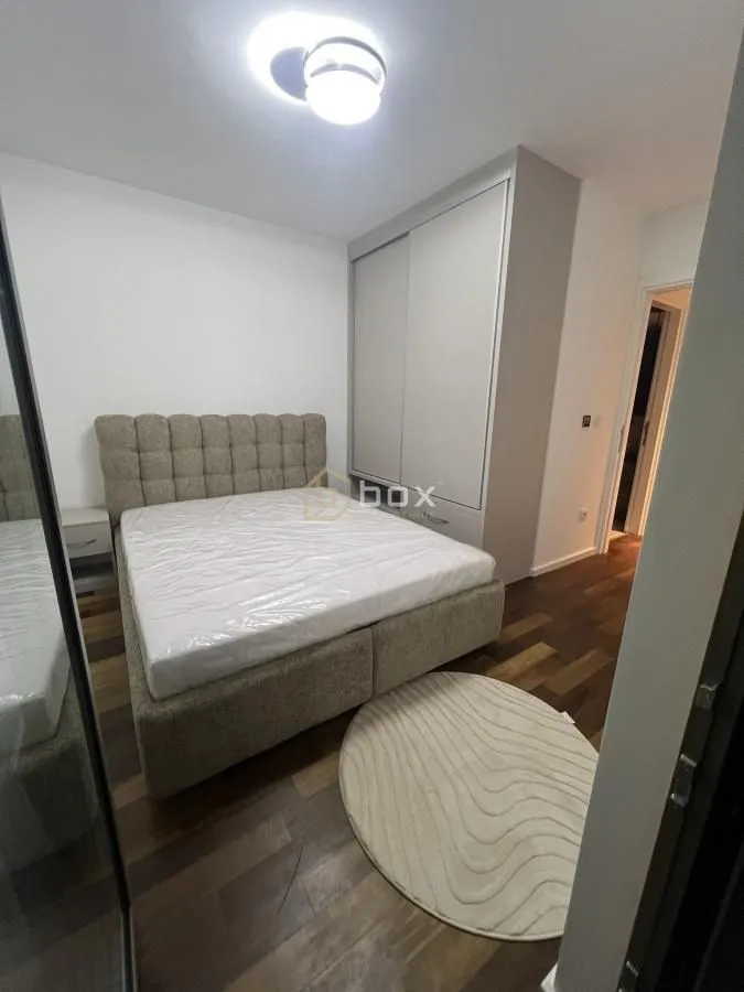 Furnished bedroom with a double bed, wardrobe, and wooden flooring.