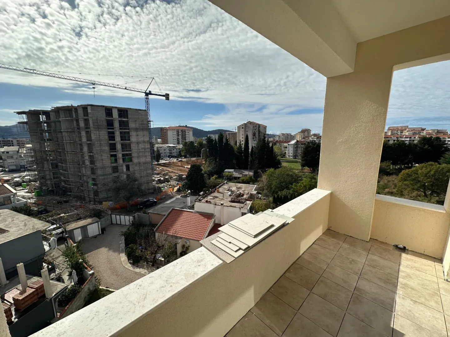 Unfurnished balcony with a view of the city and surrounding buildings under construction.