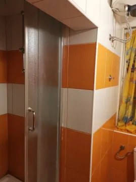 Bathroom with a shower cabin and orange and white tiles. - image 9