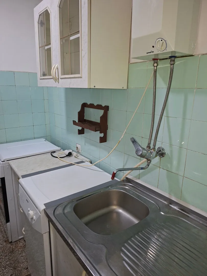 Older kitchen with a sink, wall cabinets, and a water heater.