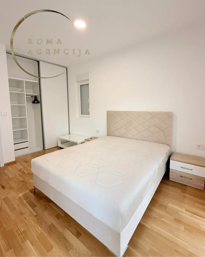 Bright bedroom with a double bed, wardrobe, and wooden flooring.