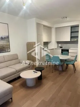 Living room with a sofa, dining area, and fitted kitchen in the background. - image 20