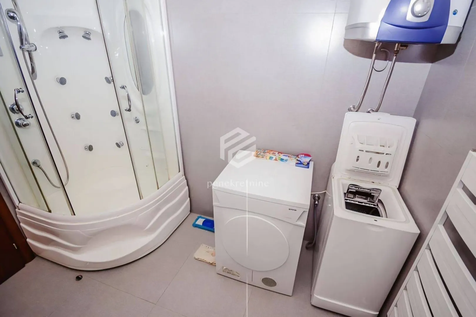 Bathroom with a shower cabin, washing and drying machine, and a water heater.