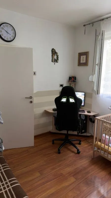Manja soba sa radnim stolom, gejming stolicom i dečijim krevetcem.
