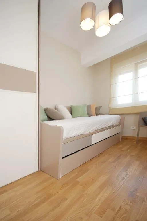 Bright children's or guest bedroom with a bed and wardrobe.