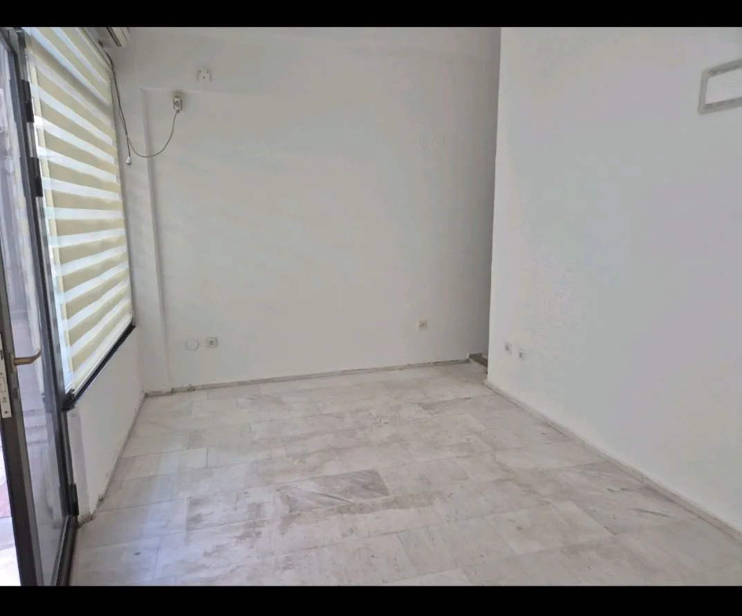 Empty room with white walls, marble floor, and balcony doors.