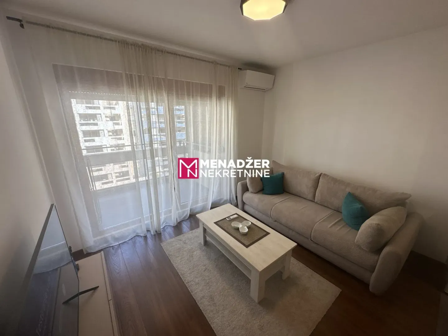 Living room with a sofa, coffee table, and balcony access.