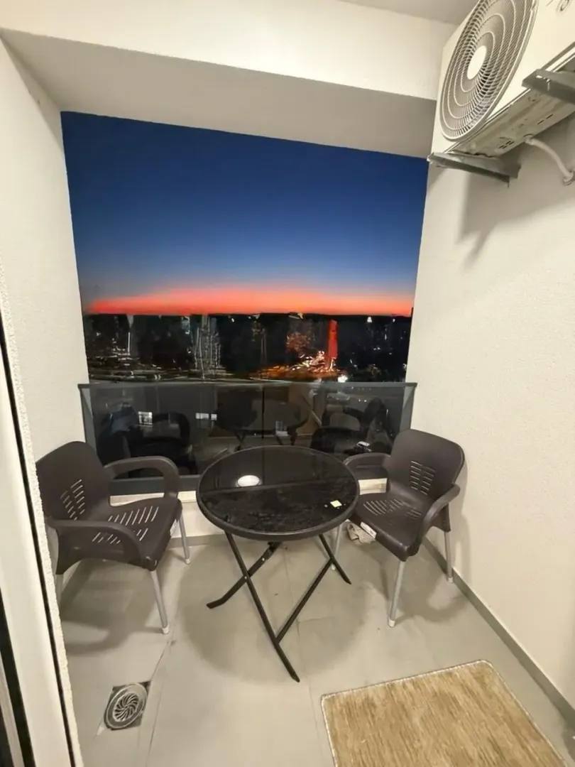 Manji namješten balkon sa stolom, stolicama i pogledom u sumrak.