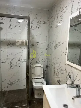 Bathroom equipped with a shower cabin, washbasin, and toilet, featuring marble-patterned ceramic tiles. - image 3