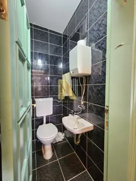 Manje kupatilo obloženo tamnim pločicama sa toaletom, umivaonikom i bojlerom. - image 9