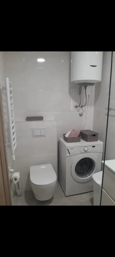 A bright bathroom with a washing machine and water heater.