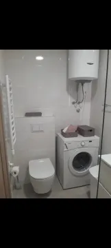 A bright bathroom with a washing machine and water heater. - image 12