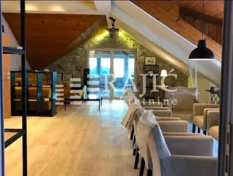 Spacious attic living room with wooden roof beams and a stone wall. - image 7