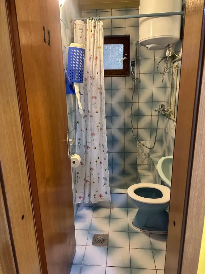 Manje kupatilo sa plavim sanitarijama i tuš kabinom.