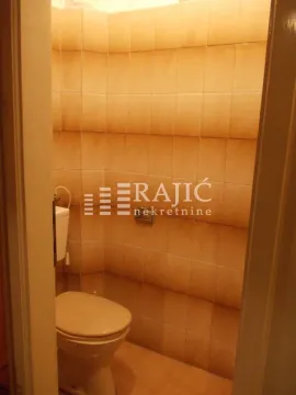 Small bathroom lined with beige ceramic tiles containing a toilet. - image 18