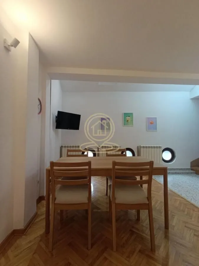 Trpezarija sa drvenim stolom i stolicama.