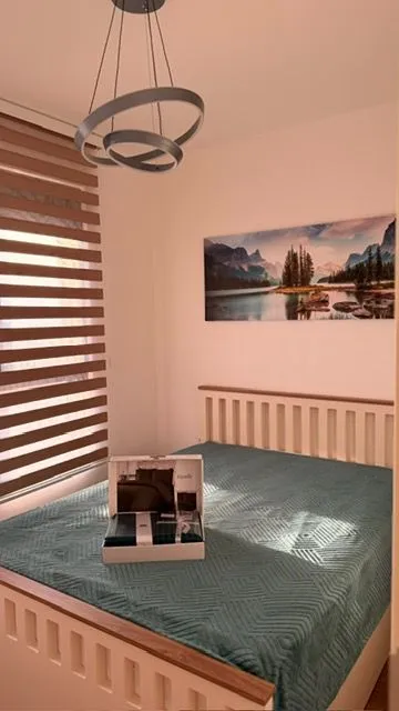 Bedroom with a double bed, window with blinds, and decorative wall art.