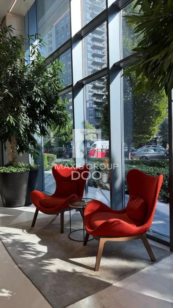 Living room with comfortable red armchairs and large glass windows.
