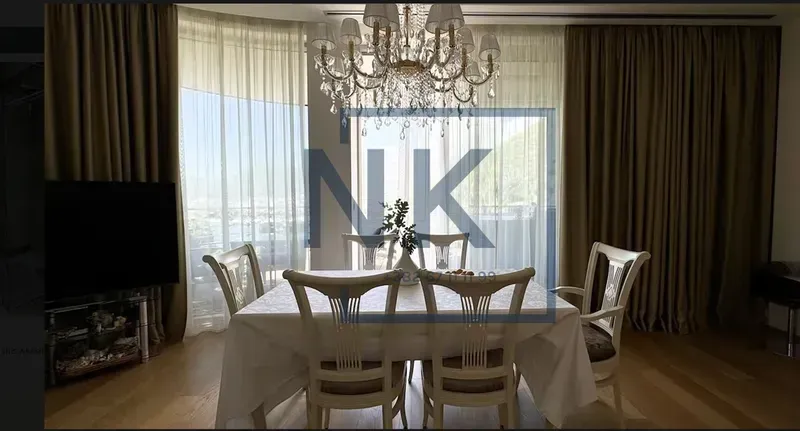 Living room with a dining table and chairs, large windows, and a chandelier.