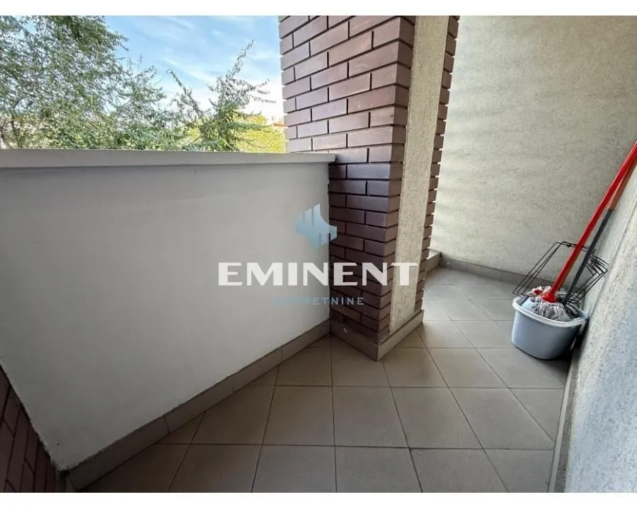 Manji popločani balkon sa ogradom i priborom za čišćenje.
