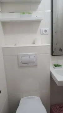 Bright bathroom with a built-in toilet tank and white tiles. - image 16