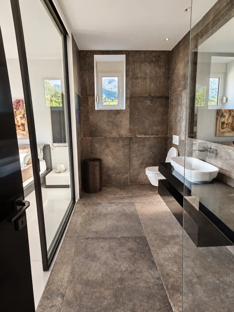 Modern bathroom with dark ceramic tiles and a washbasin.