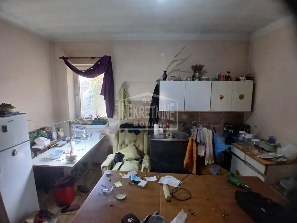 Starija kuhinja sa elementima i trpezarijskim stolom.