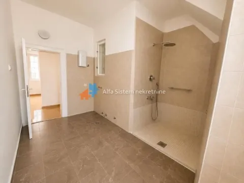 Spacious bathroom with a walk-in shower tiled throughout. - image 5