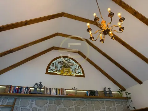 Pogled na visoki plafon sa drvenim gredama, lusterom i polukružnim vitražom. - image 25