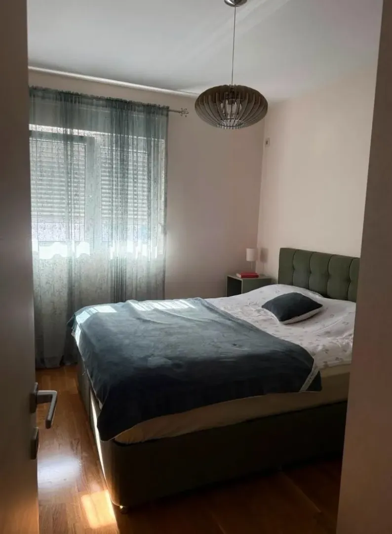 Furnished bedroom with a double bed, window, and ceiling lamp.