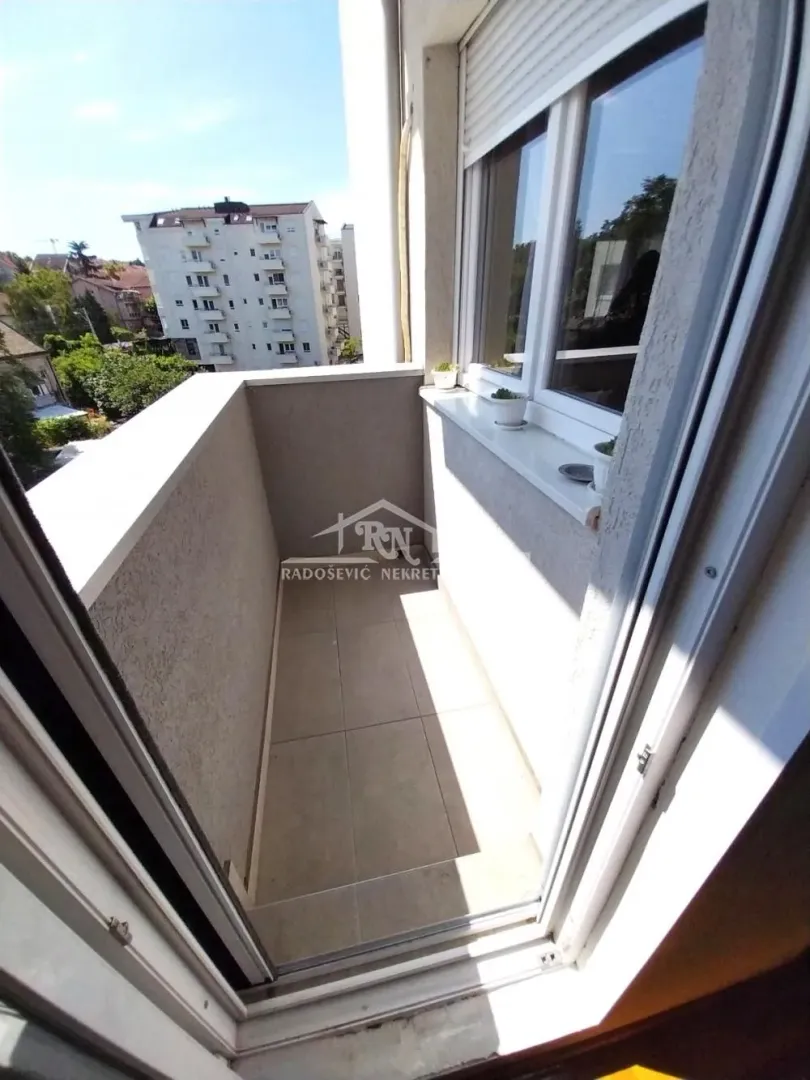 View of a smaller tiled balcony with a railing and a view of the city neighborhood.