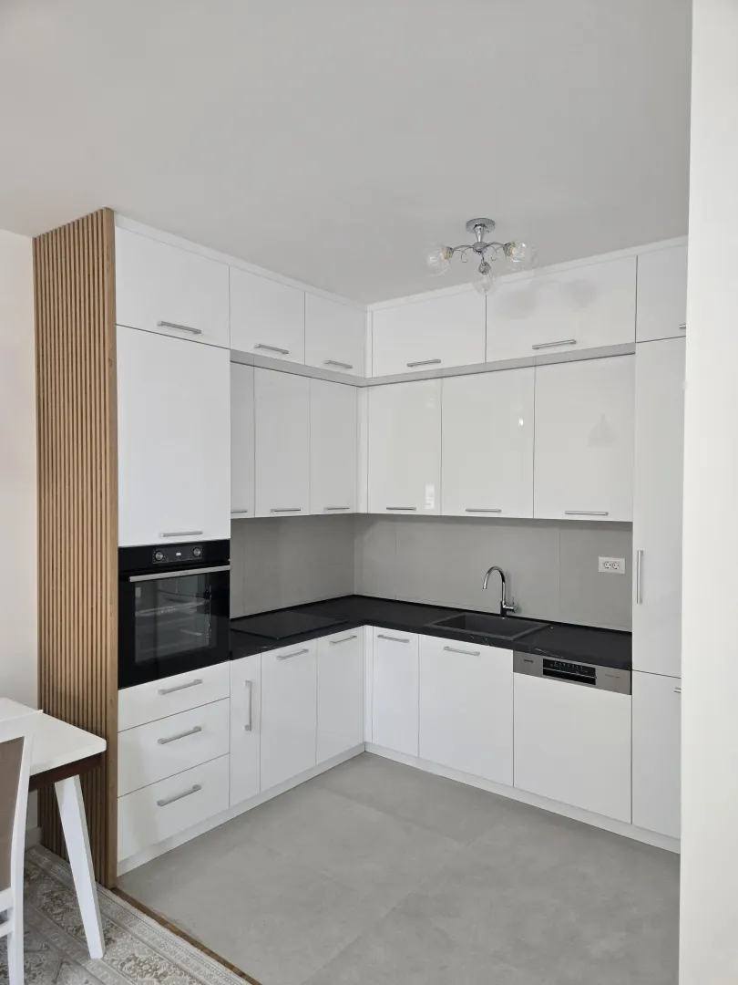 Modern white kitchen with built-in appliances and a black countertop.