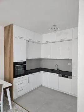 Modern white kitchen with built-in appliances and a black countertop. - image 9