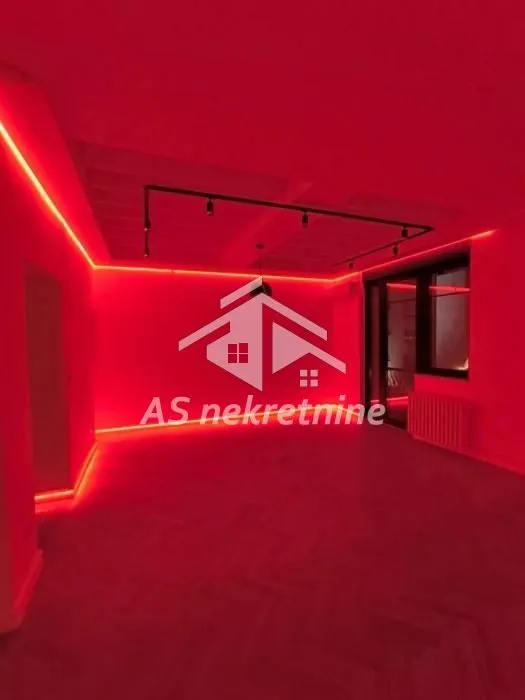 Prazna prostorija sa crvenom LED rasvetom i parketom na podu.