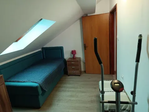 Attic room furnished with a bed, nightstand, and exercise equipment. - image 5