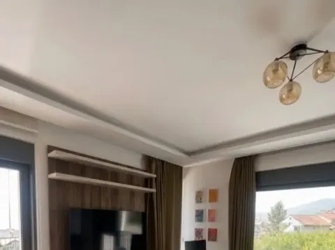 Dnevna soba sa televizorom, spuštenim plafonom i modernim lusterom. - image 4