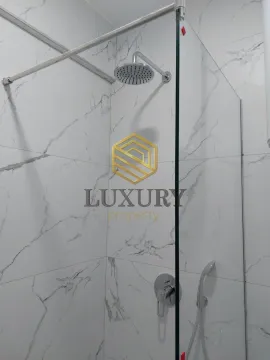 Modern walk-in shower with marble-look tiles and overhead shower head. - image 6