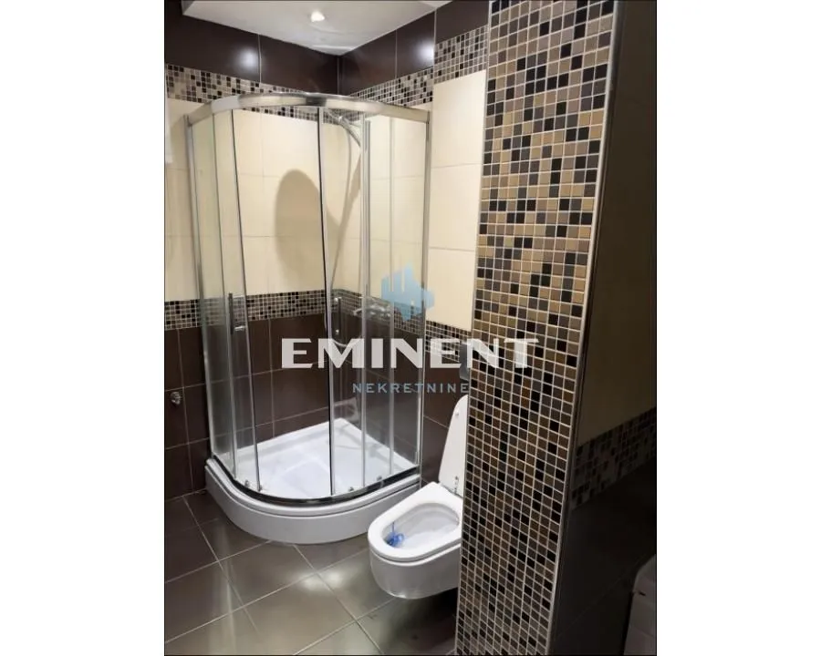 Bathroom with a shower cabin and toilet, tiled with ceramic tiles.