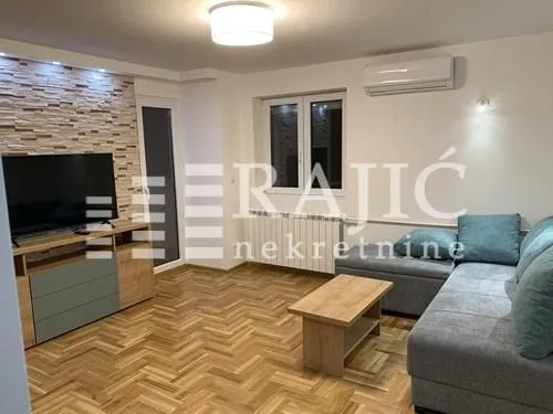 Living room with a sofa set, TV, and parquet flooring.