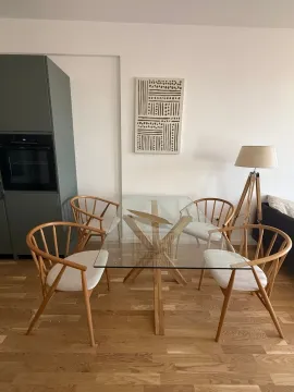 Dining area with a glass table, wooden chairs, and wall decoration. - image 6