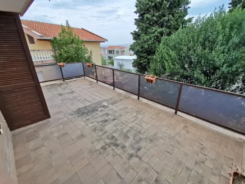 Prostrana popločana terasa sa ogradom i pogledom na okolno zelenilo i kuće. - image 3