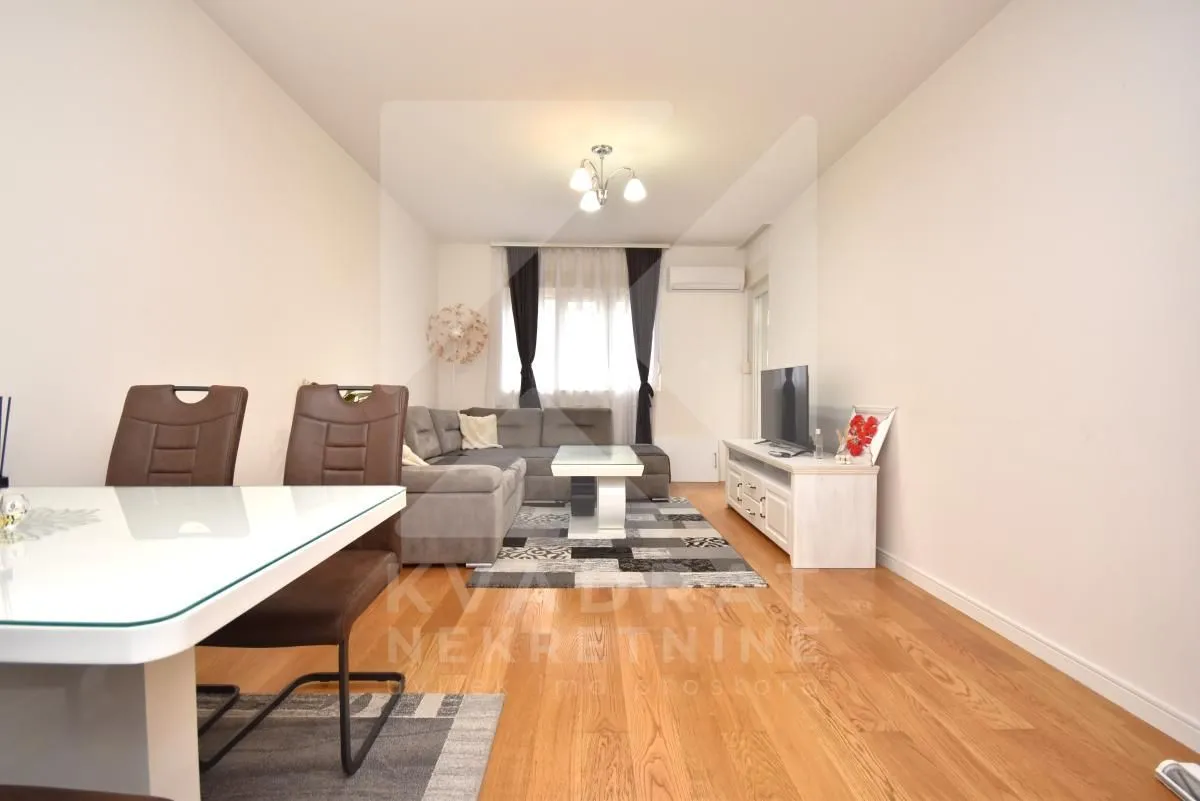 Living room with sofa, TV unit and dining table.