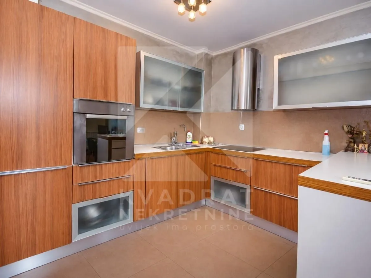 Kitchen equipped with wooden cabinetry, built-in oven, and range hood.
