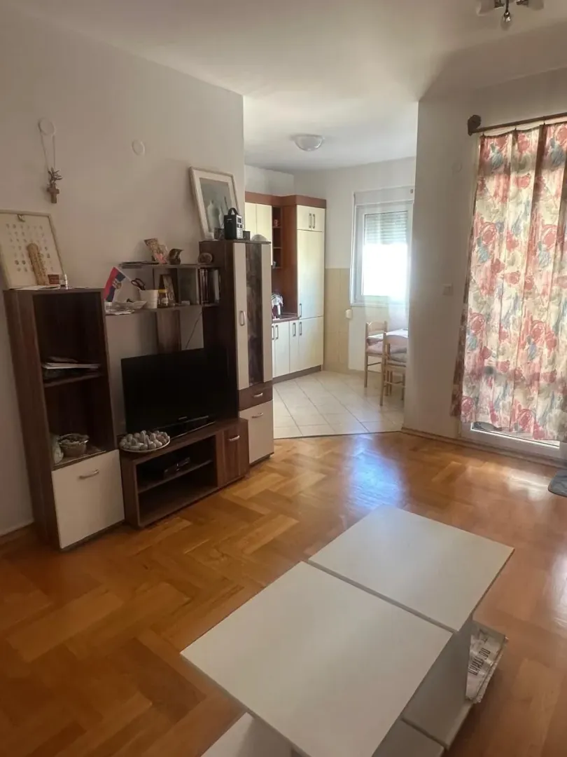 Dnevni boravak sa parketom i pogledom prema kuhinji.